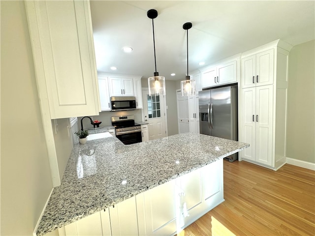 kitchen with appliances with stainless steel finishes, kitchen peninsula, light hardwood / wood-style flooring, and sink