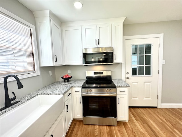 kitchen with white cabinetry, stainless steel appliances, sink, and light wood-type flooring