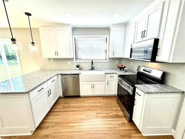 kitchen with white cabinets, light wood-type flooring, stainless steel appliances, sink, and decorative light fixtures