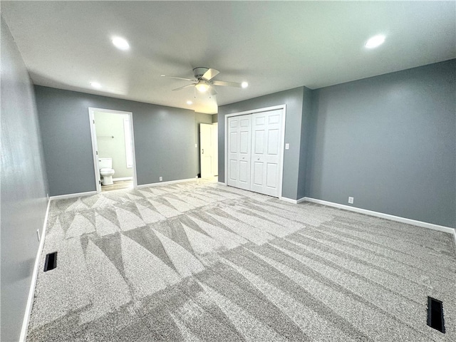 unfurnished bedroom with a closet, ceiling fan, light carpet, and ensuite bathroom