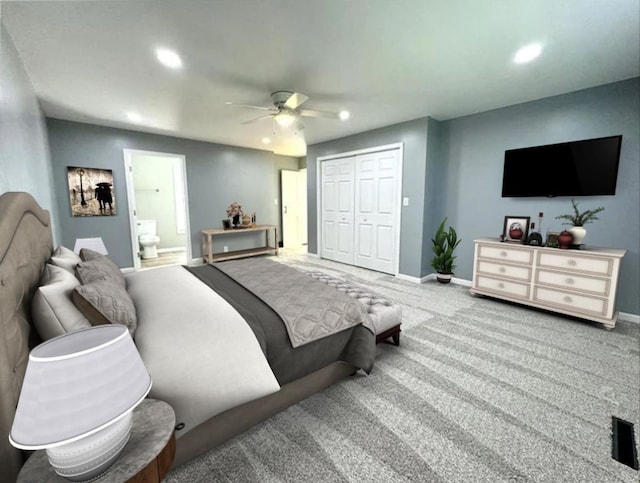 carpeted bedroom with a closet, ceiling fan, and ensuite bath