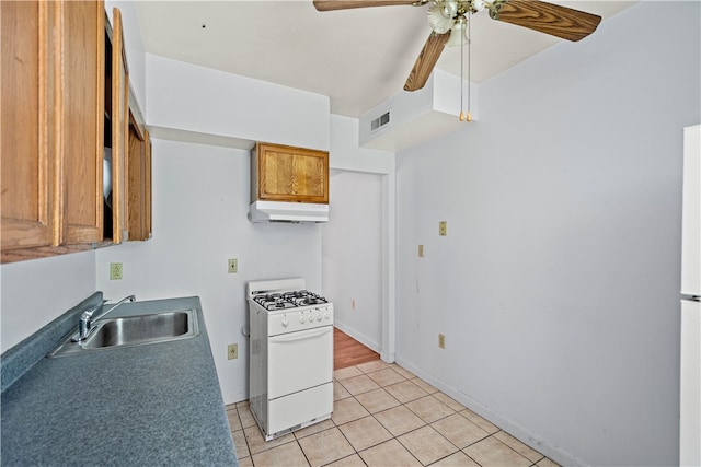 kitchen with white gas range, light tile patterned floors, sink, and ceiling fan