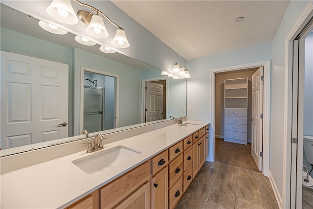 bathroom with vanity, a textured ceiling, a shower with shower door, and toilet