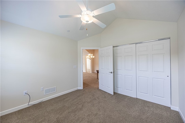 unfurnished bedroom featuring ceiling fan with notable chandelier, carpet, a closet, and lofted ceiling