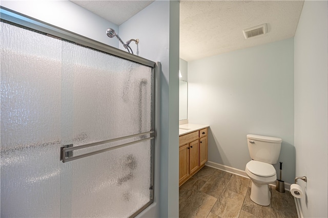 bathroom with a textured ceiling, walk in shower, vanity, and toilet