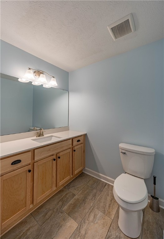 bathroom featuring a textured ceiling, vanity, and toilet