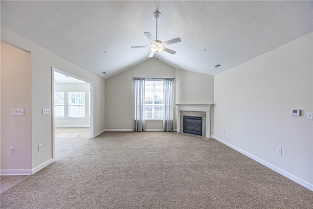 unfurnished living room featuring a high end fireplace, a textured ceiling, vaulted ceiling, carpet floors, and ceiling fan