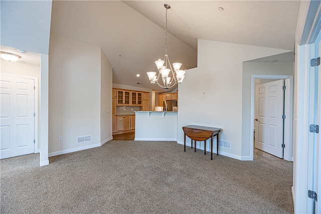 carpeted spare room featuring lofted ceiling and a chandelier