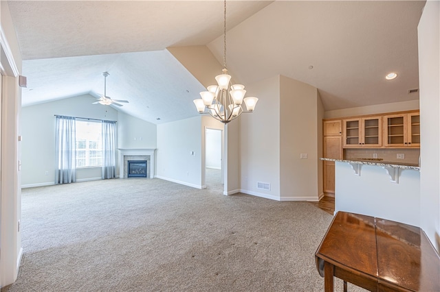 unfurnished living room featuring light colored carpet, ceiling fan with notable chandelier, and vaulted ceiling