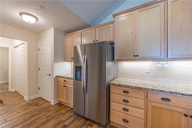 kitchen featuring a textured ceiling, stainless steel refrigerator with ice dispenser, dark hardwood / wood-style floors, and light stone countertops