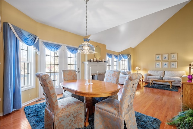 dining space with light hardwood / wood-style flooring, a healthy amount of sunlight, and lofted ceiling