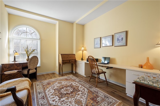 office with built in desk and dark wood-type flooring