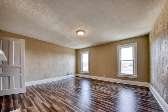 empty room with a textured ceiling and dark hardwood / wood-style flooring