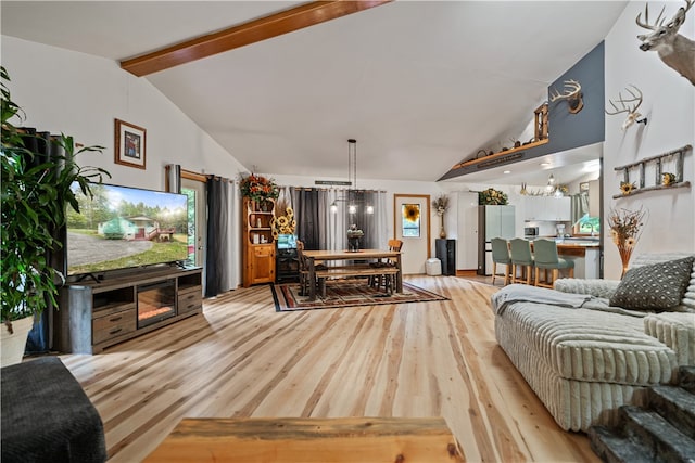 living room featuring light hardwood / wood-style floors, lofted ceiling with beams, and a chandelier