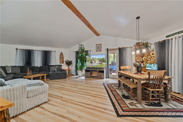 dining space featuring lofted ceiling with beams, a chandelier, and light hardwood / wood-style floors