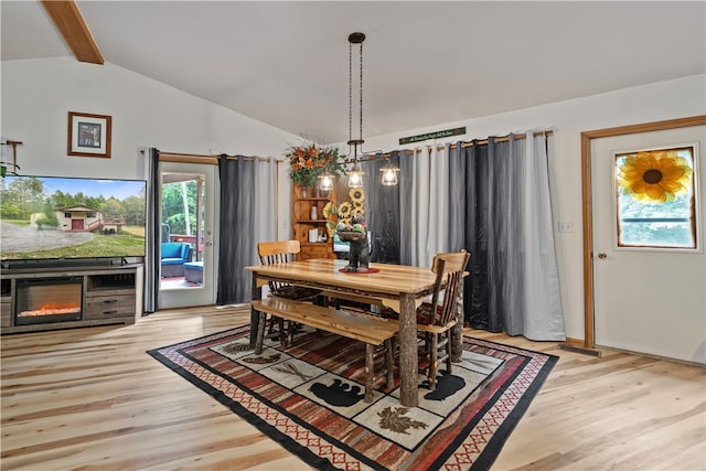 dining area featuring vaulted ceiling with beams, an inviting chandelier, and light wood-type flooring