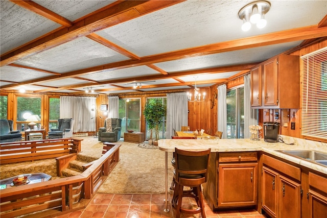 kitchen with light tile patterned floors, kitchen peninsula, a textured ceiling, decorative light fixtures, and a chandelier