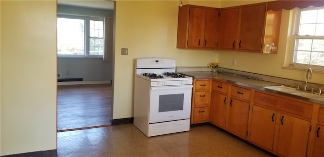 kitchen with light hardwood / wood-style floors, white gas range, and sink