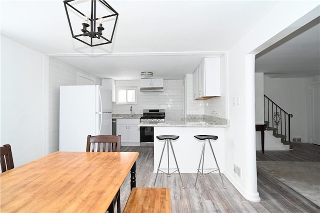 kitchen with tasteful backsplash, light hardwood / wood-style flooring, stainless steel range oven, white refrigerator, and white cabinets