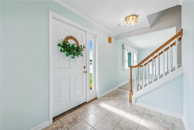 entryway with light tile patterned floors and crown molding