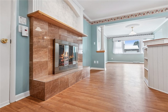 unfurnished living room featuring decorative columns, hardwood / wood-style flooring, and ornamental molding