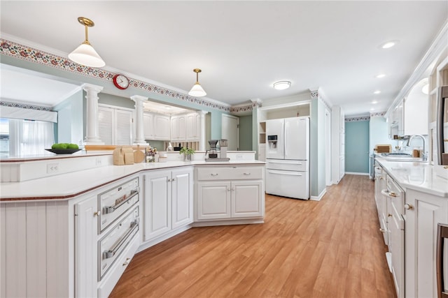 kitchen featuring hanging light fixtures, white cabinetry, ornate columns, and white fridge with ice dispenser