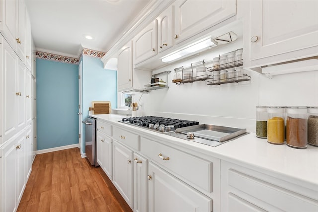 kitchen featuring white cabinets, stainless steel gas stovetop, light wood-type flooring, and crown molding