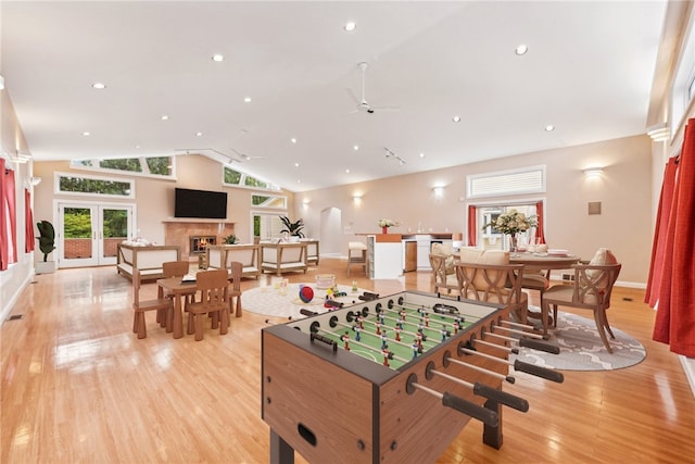 recreation room featuring high vaulted ceiling, french doors, and light hardwood / wood-style floors