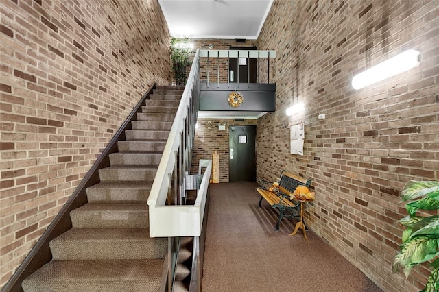 staircase with brick wall and carpet flooring