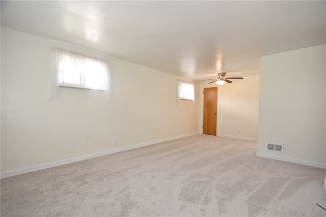 empty room featuring ceiling fan, light colored carpet, and a healthy amount of sunlight