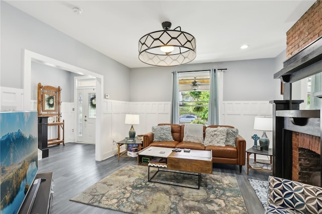 living room with a fireplace and dark wood-type flooring