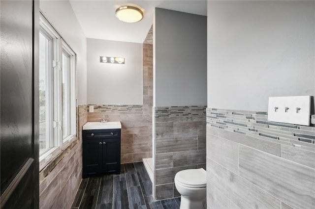 bathroom featuring tile walls, hardwood / wood-style floors, vanity, and toilet