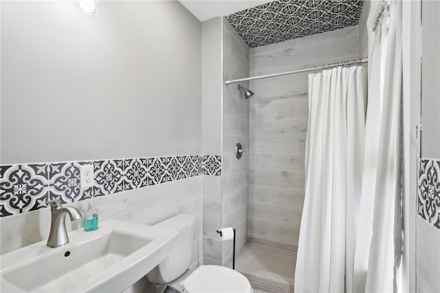 bathroom with tile walls, a shower with curtain, toilet, and sink