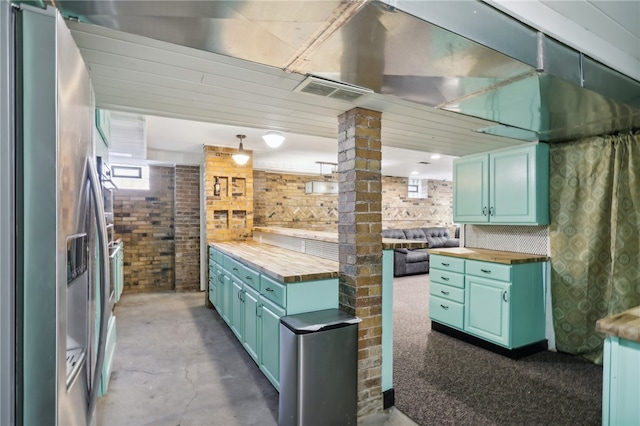 kitchen featuring butcher block counters, stainless steel fridge with ice dispenser, and brick wall