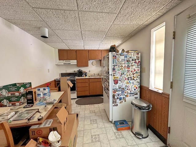 kitchen featuring wooden walls, a paneled ceiling, sink, and white appliances