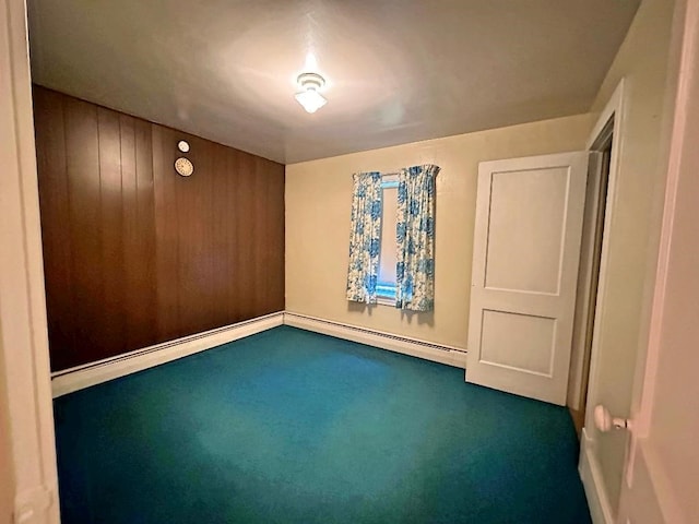 spare room with carpet, wood walls, and baseboard heating