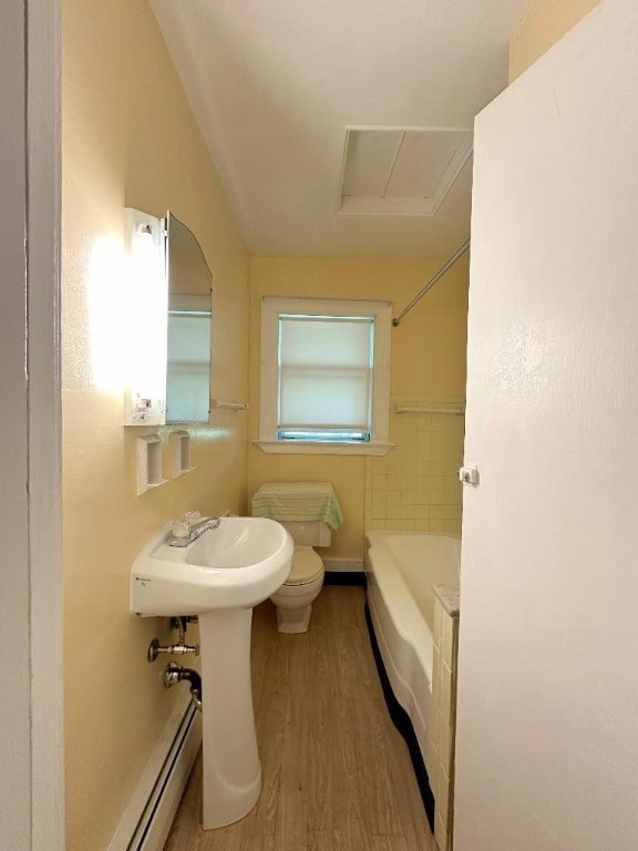 bathroom featuring hardwood / wood-style flooring, baseboard heating, bathing tub / shower combination, and toilet