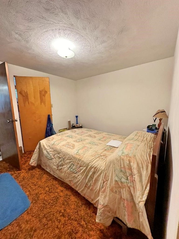 bedroom featuring dark carpet and a textured ceiling