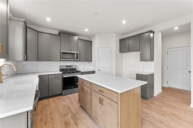 kitchen featuring sink, light hardwood / wood-style flooring, gray cabinets, appliances with stainless steel finishes, and a kitchen island