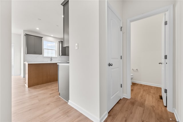 corridor with sink and light hardwood / wood-style flooring