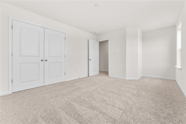 unfurnished bedroom with light colored carpet and a closet