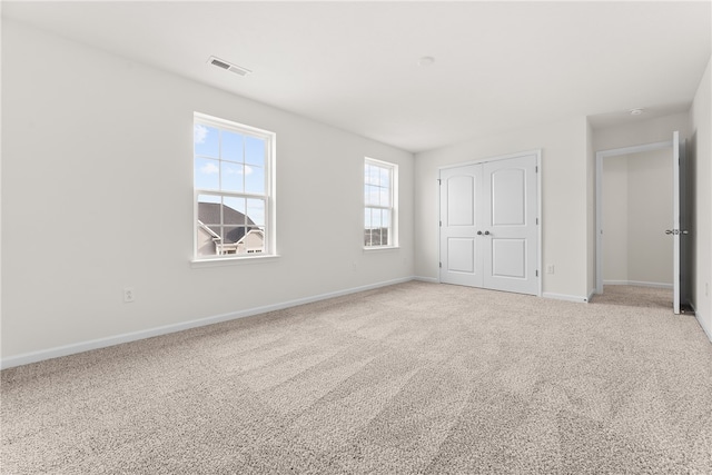 unfurnished bedroom with light carpet and a closet