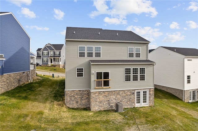 rear view of property with a lawn, central AC, and french doors