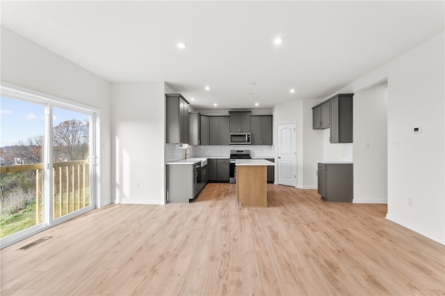 kitchen featuring sink, gray cabinets, appliances with stainless steel finishes, tasteful backsplash, and light hardwood / wood-style floors