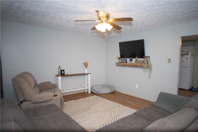 living room featuring wood-type flooring, ceiling fan, and a textured ceiling