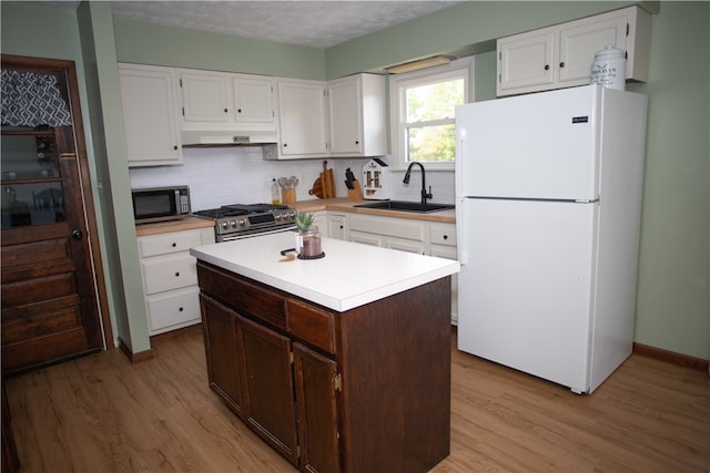 kitchen with sink, a kitchen island, dark brown cabinets, appliances with stainless steel finishes, and light wood-type flooring