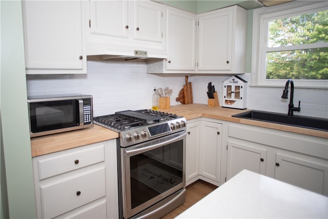 kitchen featuring backsplash, sink, stainless steel appliances, and white cabinets