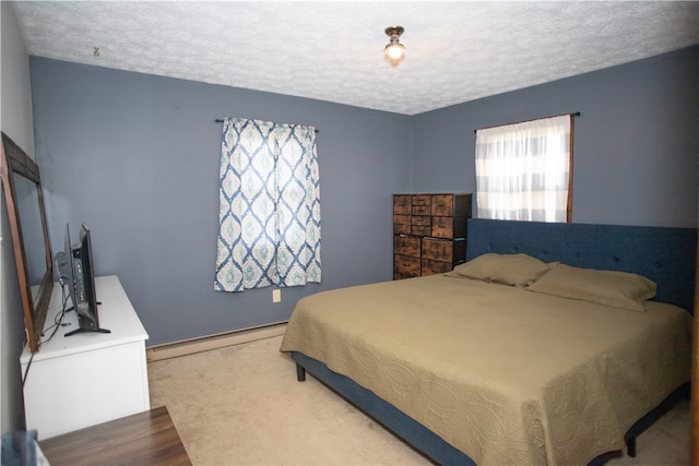 bedroom with a baseboard radiator, a textured ceiling, and carpet floors