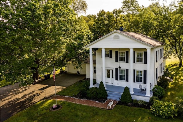 neoclassical / greek revival house featuring a porch, a front lawn, an outdoor structure, and a garage