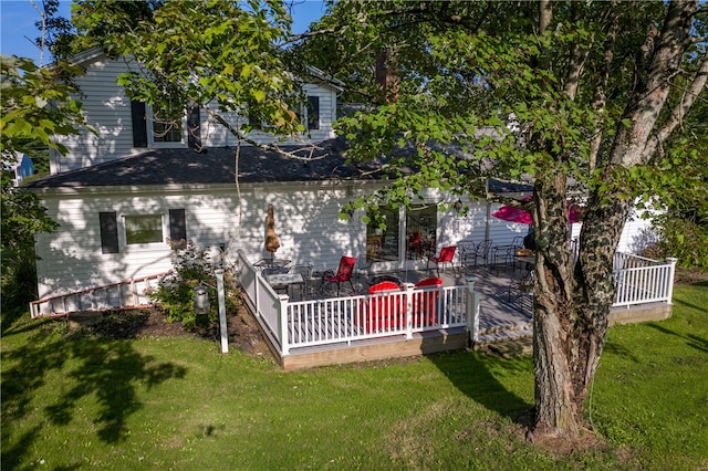 back of property featuring a wooden deck and a lawn